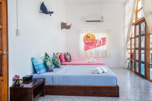 um quarto com uma cama com lençóis azuis e um sofá rosa em Tamtawan Guesthouse - ตามตะวันเกสเฮ้าส์ em Ko Lipe
