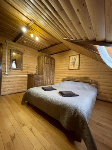 a bedroom with a bed in a log cabin at Guest House Zator in Vyshkiv