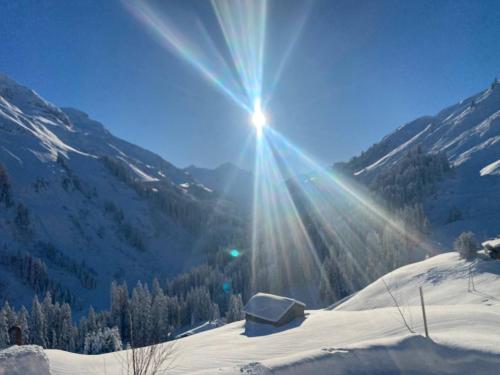 a sun shining on a snow covered mountain at Älpler Stuba Appartements am Lärchenhof in Warth am Arlberg