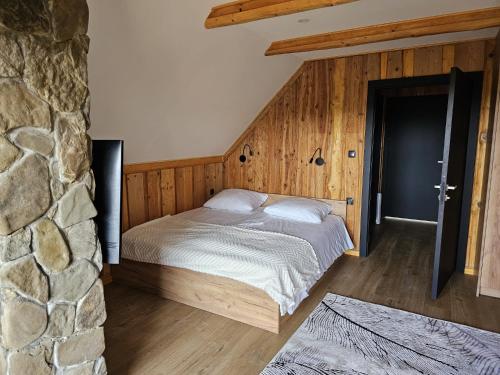 a bed in a room with a stone wall at Domek LUNA in Olchowiec