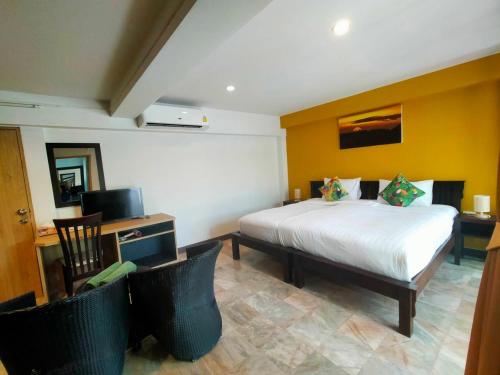 a bedroom with a large bed and two chairs at Kamala Beachfront Apartment in Kamala Beach