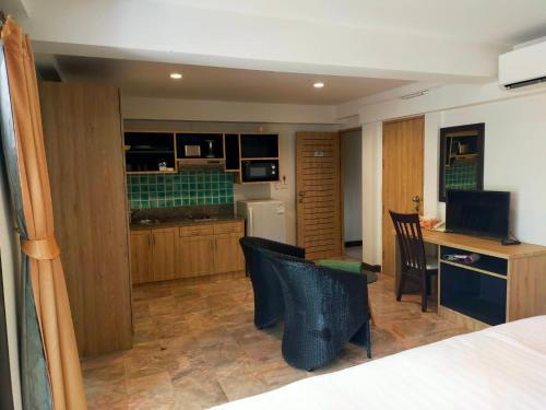 a room with a bed and a kitchen with a desk and chairs at Kamala Beachfront Apartment in Kamala Beach