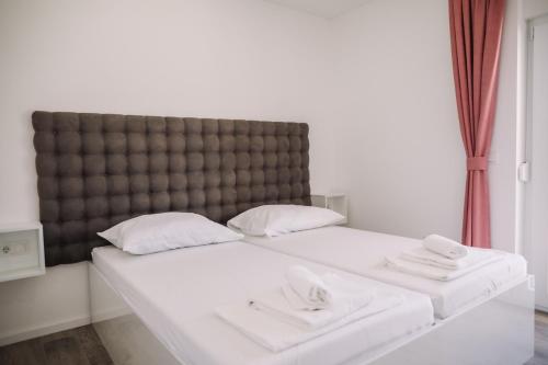 1 cama con 2 almohadas blancas y cabecero grande en Sunshine Villa, en Novalja