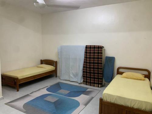 um quarto com duas camas e um tapete no chão em Zahra Homestay em Rantau Panjang
