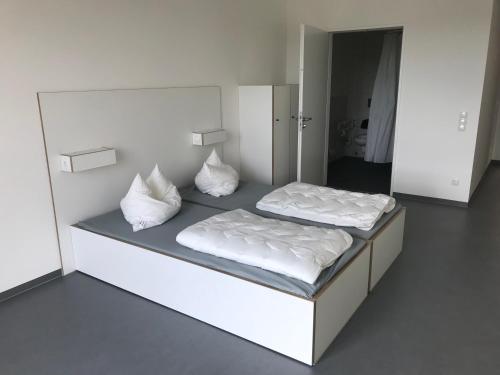 1 dormitorio con 2 camas con sábanas y almohadas blancas en Jugendherberge Heilbronn en Heilbronn