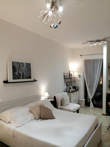 a white bedroom with a bed and a chandelier at B&B Villa Nonna Maria in Castellana Grotte