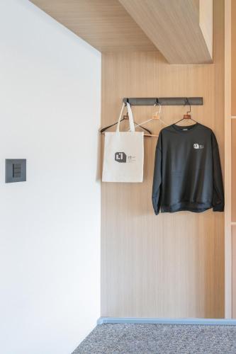 a black shirt and a white bag on a wall at Apartment Hotel 11 Namba Minami in Osaka