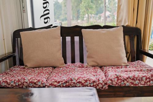 a couch with two pillows on it with a window at ไร่นภาดลรีสอร์ท in Mae Suai