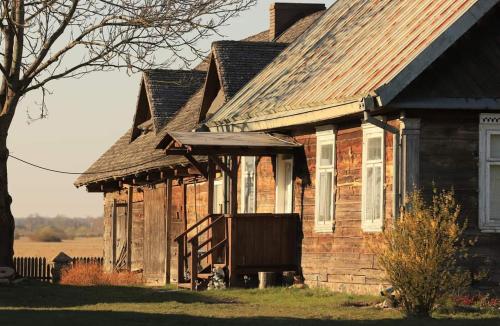 an old wooden house with a gambrel roof at Filipówka in Sztabin
