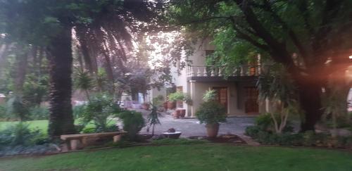 a view of a house with trees and a yard at De Stallen Guest Villas and Golf Course in Bloemfontein