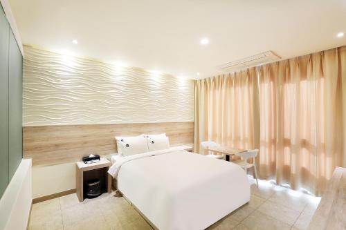 a bedroom with a white bed and a desk at Hotel The Sea Star in Incheon
