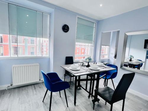 a dining room with a table and blue chairs at Hyde Park Studio Flats in London