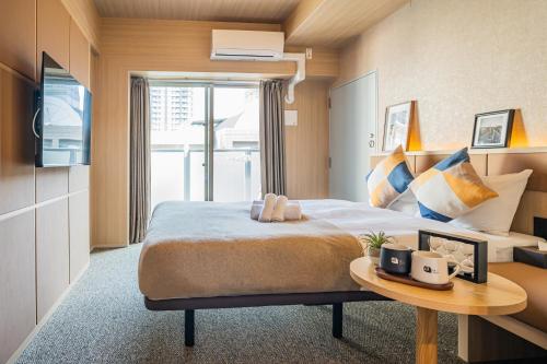 pokój hotelowy z łóżkiem i stołem w obiekcie Apartment Hotel 11 Namba Minami w Osace