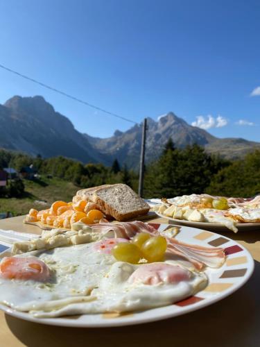 波德戈里察的住宿－Mountine cottage Hajdi Komovi，餐桌上放着食物的盘子,背后是山地