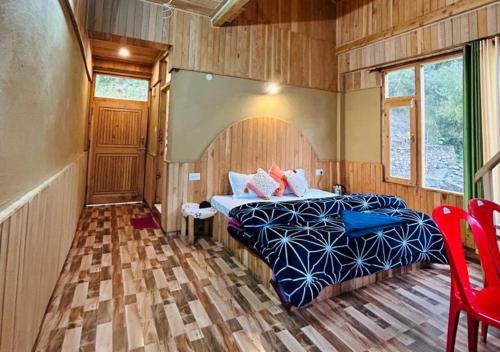 ein Schlafzimmer mit einem Bett in einem Zimmer mit Holzwänden in der Unterkunft Mountain Bliss Cottages by StayApart in Shoja