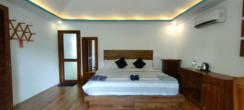 um quarto com uma cama branca e almofadas pretas em The Coast Beach Resort em Agonda