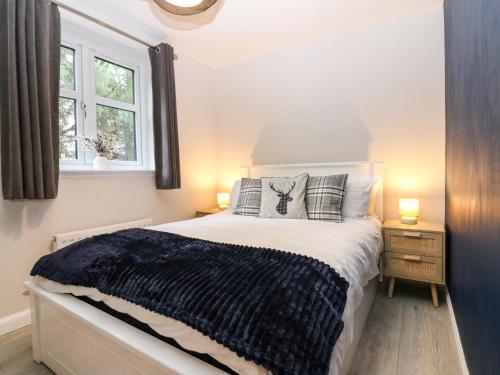 a bedroom with a bed and two lamps and a window at 11 Ambleside Court in Banchory