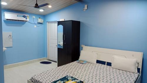 Serene Homestay (Mini -For 2 to 3 Guest) في باناجي: غرفة نوم بسرير وجدار ازرق
