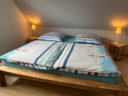 a bed with a blue and white comforter and two lamps at Ferienwohnung am Selenter See in Selent