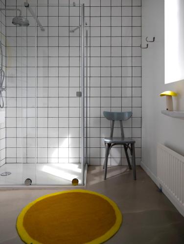 La salle de bains est pourvue d'une douche avec un tapis jaune et un tabouret. dans l'établissement La Maison Plûme, à Villequier