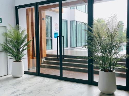 two potted plants in front of a glass door at Sand Dance Hotel in Prachuap Khiri Khan