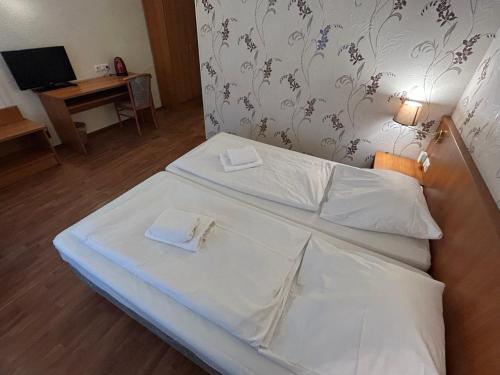 una camera con due letti con lenzuola bianche e una televisione di WestEnd#201 a Francoforte sul Meno