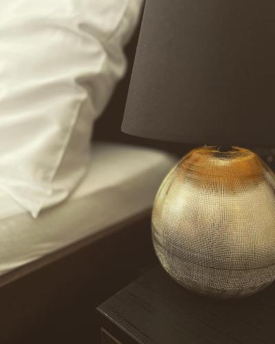 a lamp sitting on a table next to a bed at Apartmány Siesta in Poľný Kesov