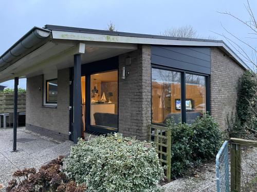 a brick house with glass doors and a roof at Beachbungalow Park Iselmar 39 aan Ijsselmeer bungalow 26 in Lemmer