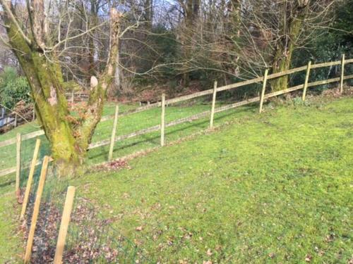 a wooden fence in a field next to a tree at BRANTLEA Detached 4 Bed Home, Hot Tub, Lake View, Parking, Pet Friendly in Bowness-on-Windermere