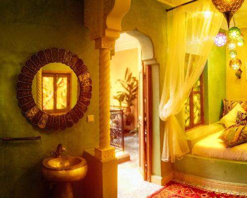 1 dormitorio con cama y espejo en Riad Persephone, en Marrakech
