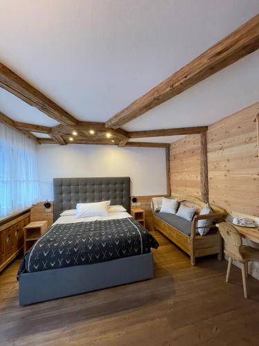 a bedroom with a bed and a couch and a table at Agriturismo Maso Corradini in Castello di Fiemme