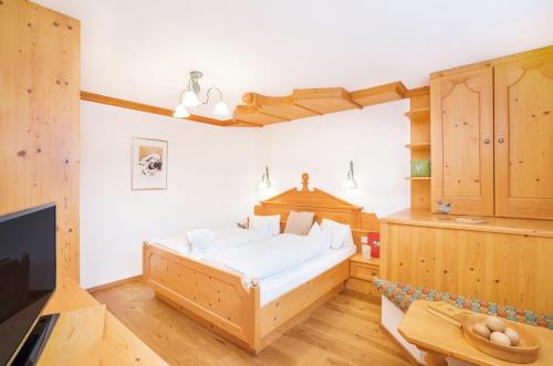 a bedroom with a bed and a tv and wooden cabinets at Biohotel Leutascherhof in Leutasch