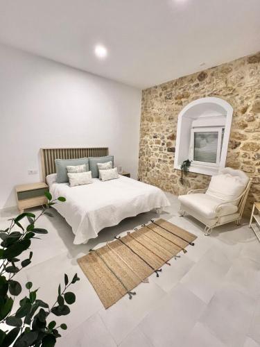 - une chambre avec 2 lits et un mur en pierre dans l'établissement Casa Abuela Ana, à Alcalá de los Gazules