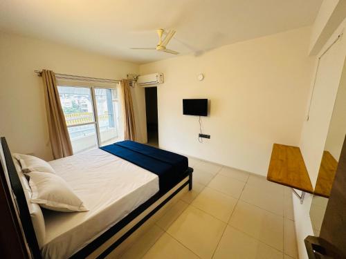 een kleine slaapkamer met een bed en een televisie bij Tanour stay in Bangalore