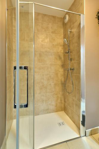une douche avec une cabine en verre dans une salle de bain dans l'établissement Le Manou, Appartement neuf avec terrasse, parking sous-terrain & ascenseur by PRIMO C0NCIERGERIE, à Nevers