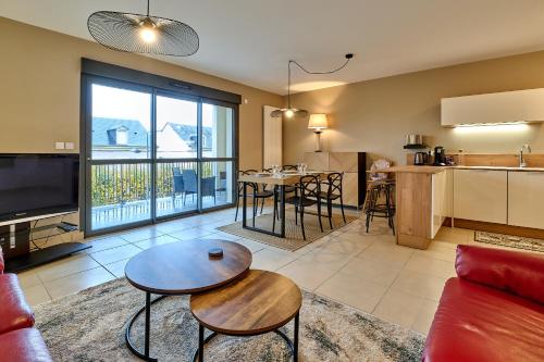 een woonkamer met een bank en een tafel bij Le Manou, Appartement neuf avec terrasse, parking sous-terrain & ascenseur by PRIMO C0NCIERGERIE in Nevers