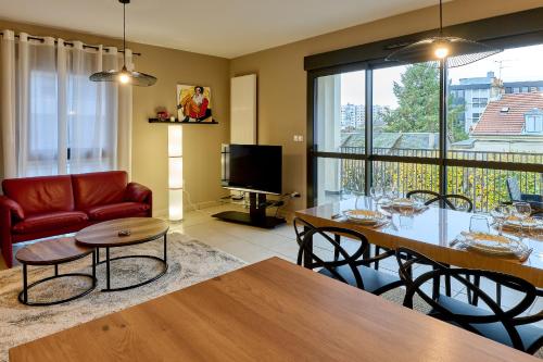 a living room with a table and chairs and a television at Le Manou, Appartement neuf avec terrasse, parking sous-terrain & ascenseur by PRIMO C0NCIERGERIE in Nevers