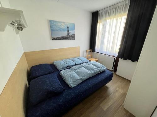 a bedroom with a blue bed and a window at Schorrebloem 34* in Nieuwvliet