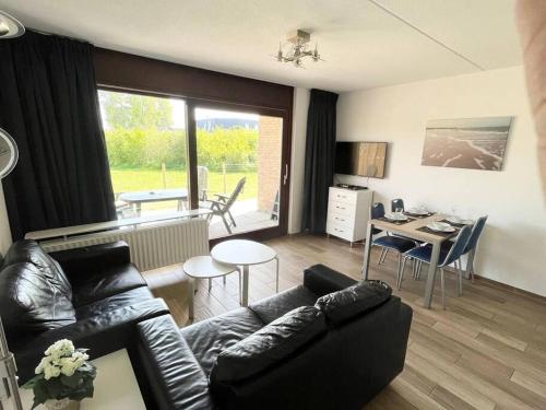 a living room with a black leather couch and a table at Schorrebloem 34* in Nieuwvliet