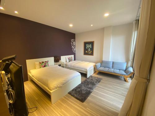1 dormitorio con 2 camas, TV y sofá en 忘憂天空民宿 en T'an-nan