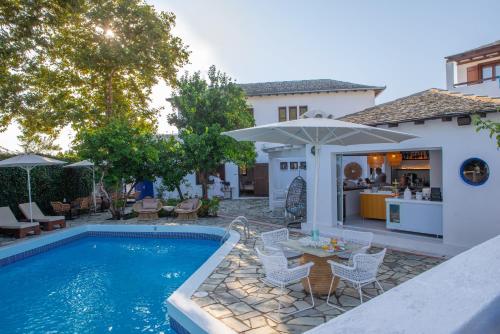 - une piscine avec des chaises et un parasol à côté d'une maison dans l'établissement Aeolos Hotel & Villas - Pelion, à Chorefto