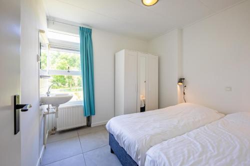 een slaapkamer met een bed, een wastafel en een raam bij Strandhuys Oester De Koog Texel in De Koog