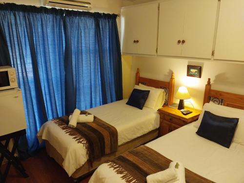 a bedroom with two beds and blue curtains at Lily Guesthouse in Bloemfontein