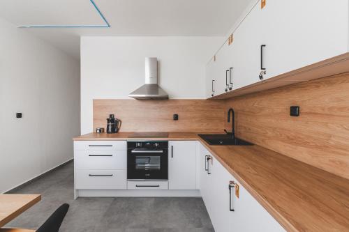 a kitchen with white cabinets and a black oven at BP Hostel / Urbinská 144 in Český Krumlov