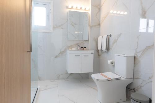 Baño blanco con aseo y lavamanos en Fig Tree Aqua Apartment-143 en Protaras