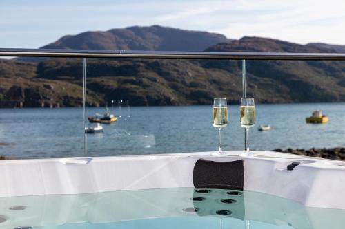 dois copos de vinho sentados numa mesa num barco em Birches Lodge with Hot Tub em Dundonnell