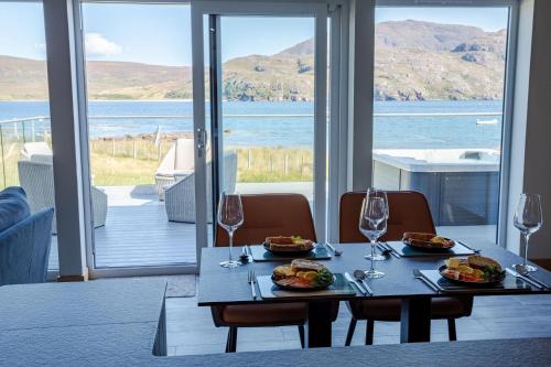 una mesa con dos platos de comida y copas de vino en Birches Lodge with Hot Tub, en Dundonnell