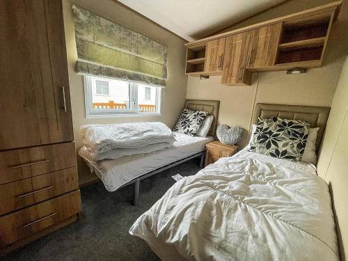 a small bedroom with two beds and a window at Beautiful 6 Berth Caravan At Caldecott Hall Country Park, Norfolk Ref 91150c in Great Yarmouth