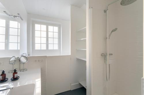 La salle de bains blanche est pourvue d'une douche et d'un lavabo. dans l'établissement Le Solent - Au cœur de l'intra-mutros, à Saint-Malo