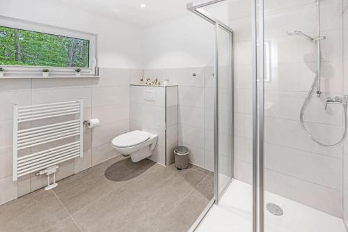 ein weißes Bad mit einem WC und einer Dusche in der Unterkunft Ferienhaus Dünenwald in Dierhagen